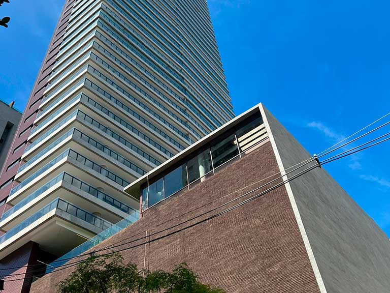 Imagem da imponente torre do Apartamento Fasano Itaim, destacando-se no skyline do bairro Itaim Bibi, em São Paulo. Com um design contemporâneo e linhas elegantes, o edifício representa o luxo e a sofisticação característicos do Grupo Fasano, oferecendo aos seus moradores uma experiência de vida única e exclusiva.
